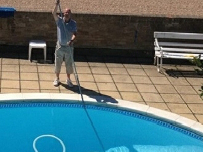 Swimming pool maintenance engineer cleaning a pool