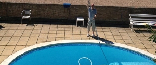 Swimming pool maintenance engineer cleaning a pool